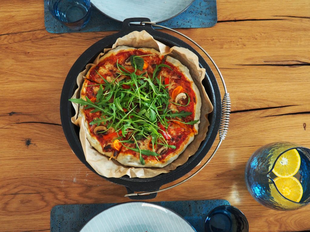 Vegetarische Dutch Oven Pizza aus dem Backofen auf Holztisch