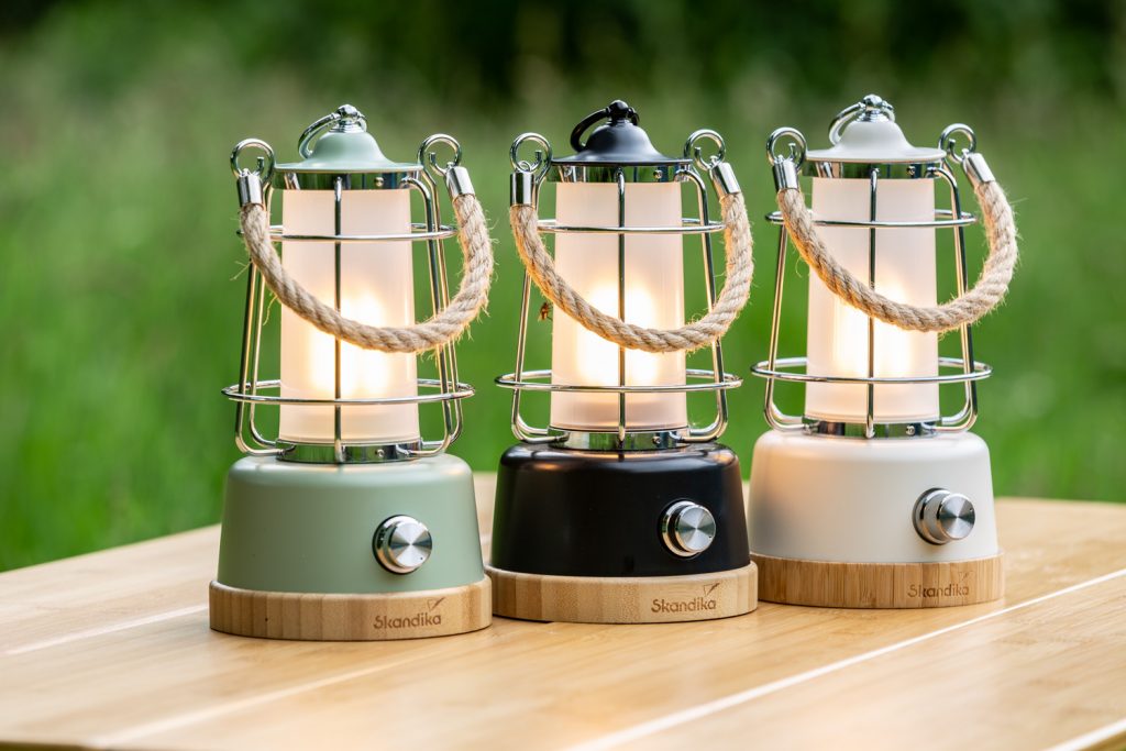 Drei Kiruna Campinglampen in verschiedenen Farben auf Bambustisch