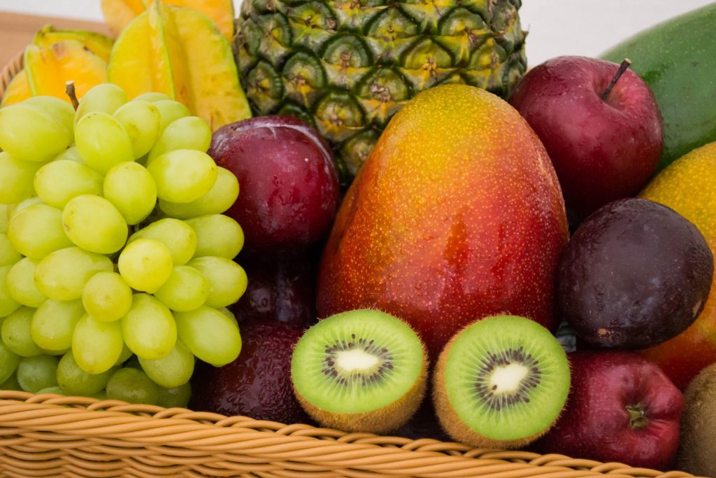 Obstkorb mit diversem Gemüse wie Kiwi, Mango, Apfel, Weintrauben und Ananas