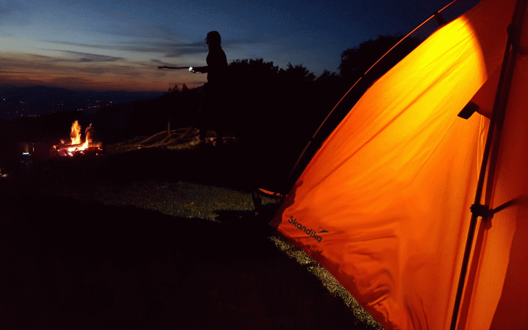 Beleuchtetes Zelt im Dunkeln mit nahegelegenem Lagerfeuer