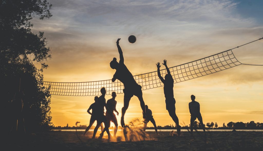 Silhouette von Sportlern beim Volleyball in der Sonne