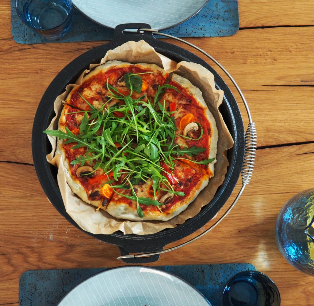 Vegetarische Dutch Oven Pizza aus dem Backofen auf Holztisch